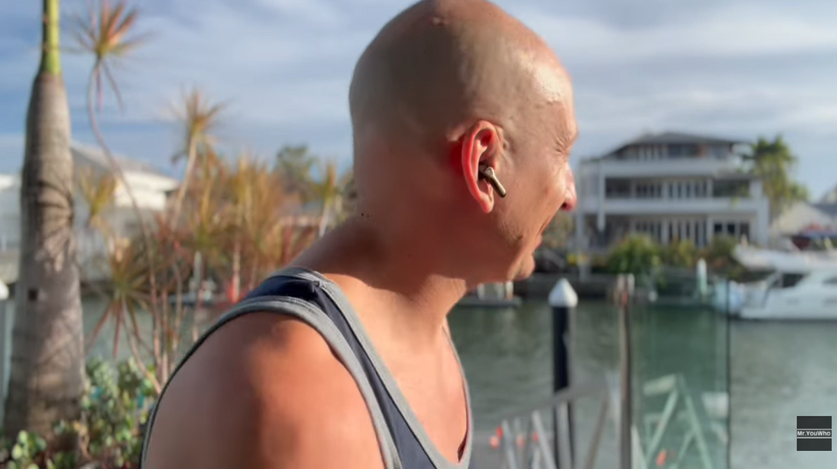 Andrew Hough testing earbuds by the water on the Gold Coast